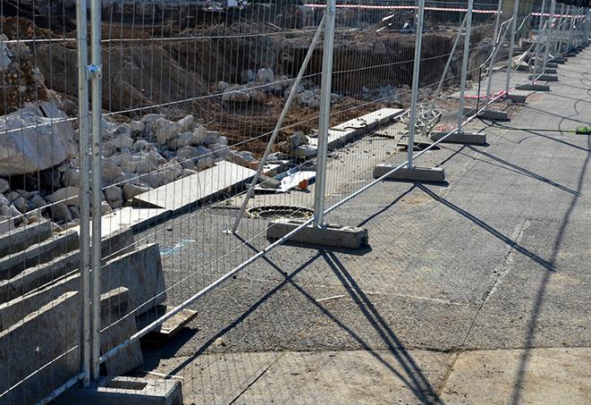 a temporary fence enclosing a job site with industrial equipment